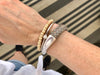 a woman's wrist with a gray braided leather bracelet with magnetic clasp and two other bracelets