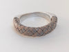 A gray braided leather bracelet with magnetic clasp sits on a white table with the braided leather facing forward