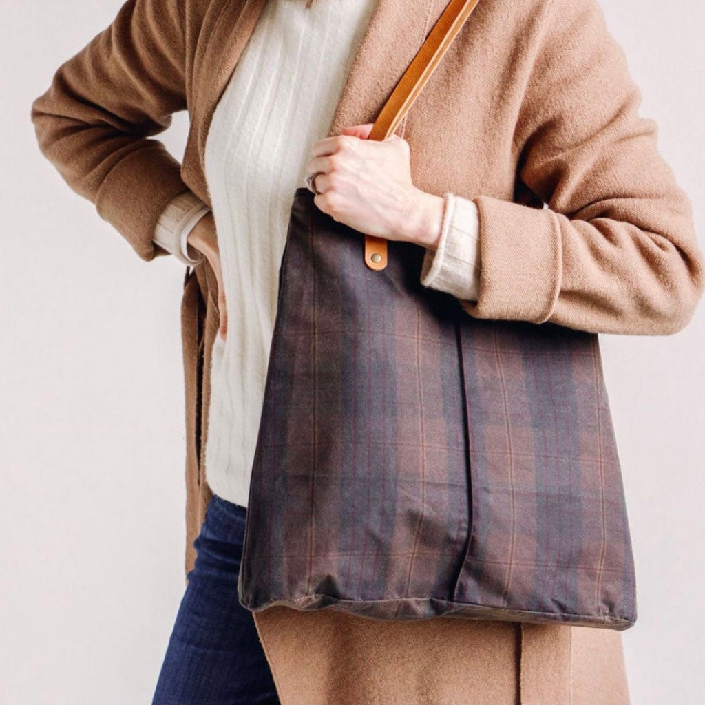 a woman hlds a Gold Brown Plaid City Tote Oil Cloth Tote while wearing a white shirt and brown sweater