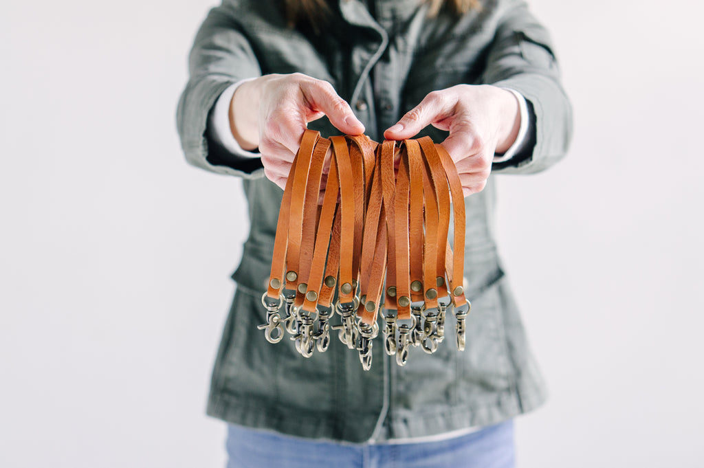 A woman holds many genuine leather wristlet straps