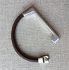 a brown leather and silver straight bar bracelet sits on a white cloth with clasp undone