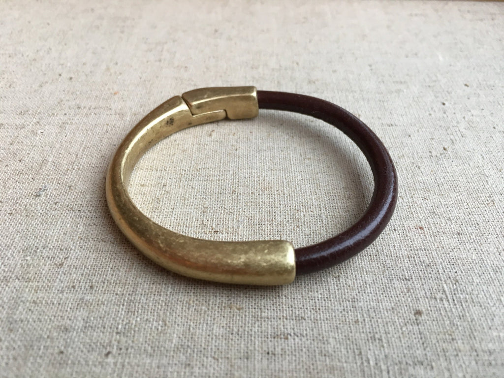 brown leather strap bracelet with antique brass clasp on white table
