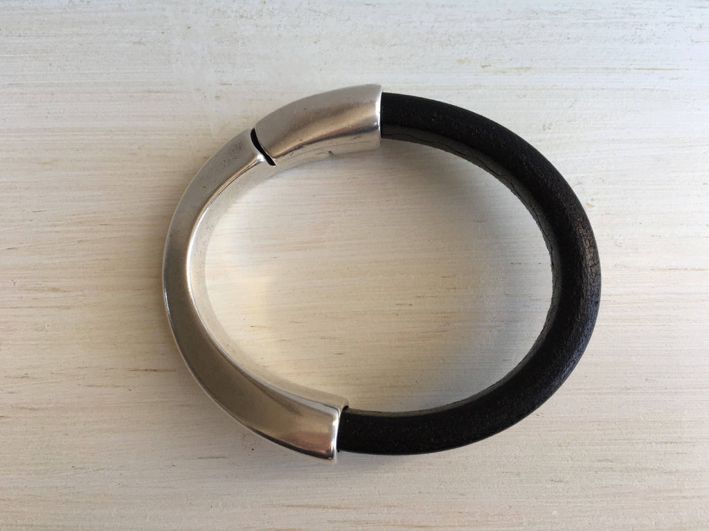 A thick black leather bracelet with silver magnetic clasp
