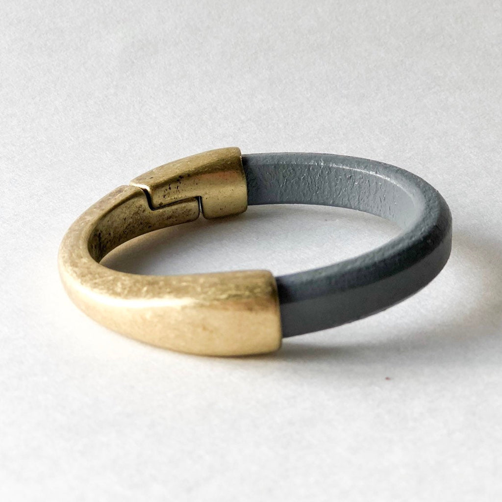 a thick gray leather bracelet with thick antique brass clasp
