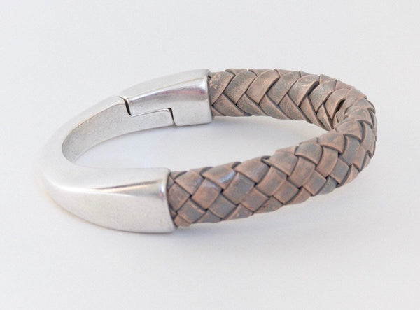a gray braided leather bracelet with magnetic clasp sits on a white table