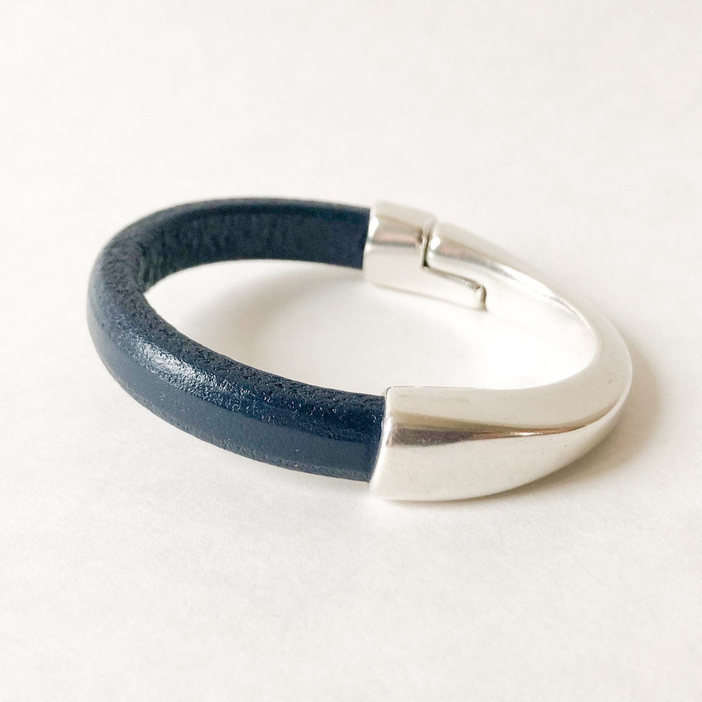 A women's navy leather bracelet sits on a white table