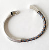 A Gray Metallic Leather Bracelet sits on a white table with hits magnetic silver clasp slightly open
