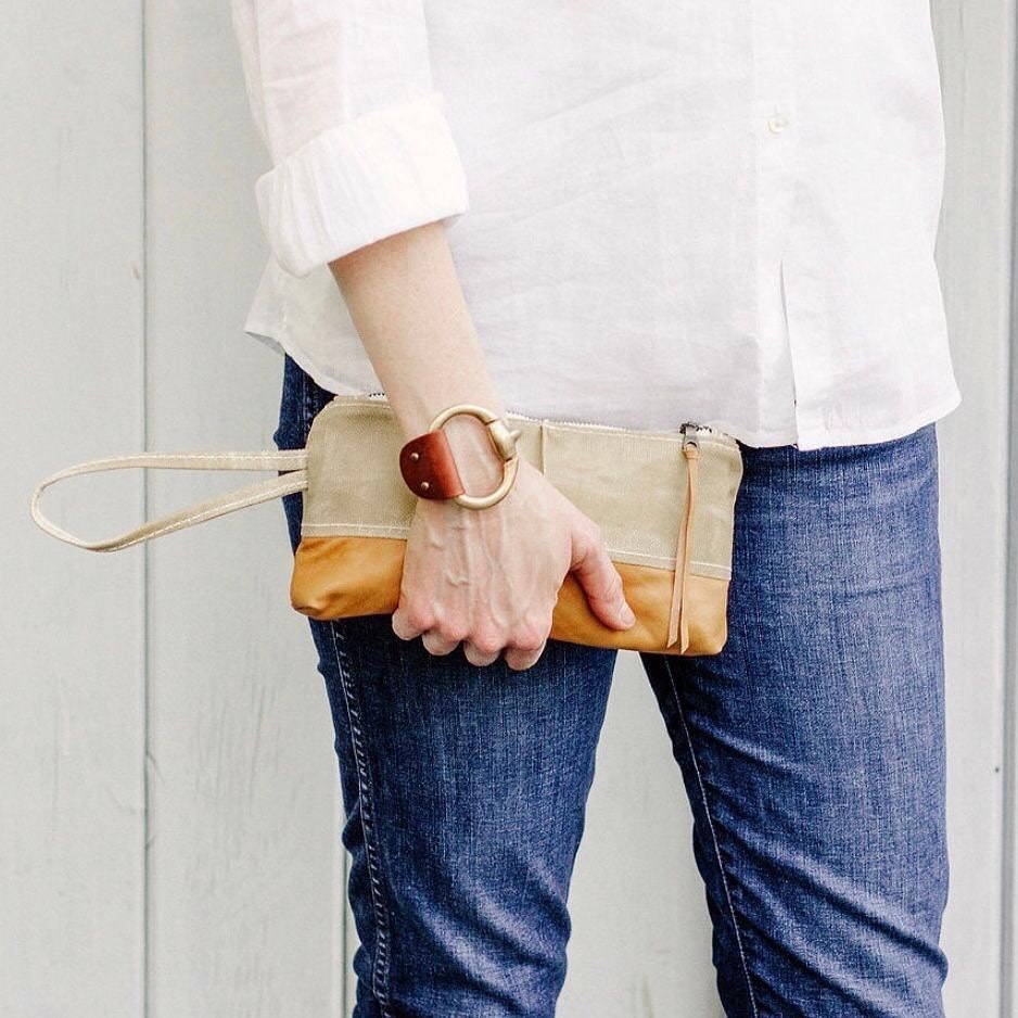 A woman wears a large snaffle bit bracelet with antique brass clasp, jeans and a white shirt