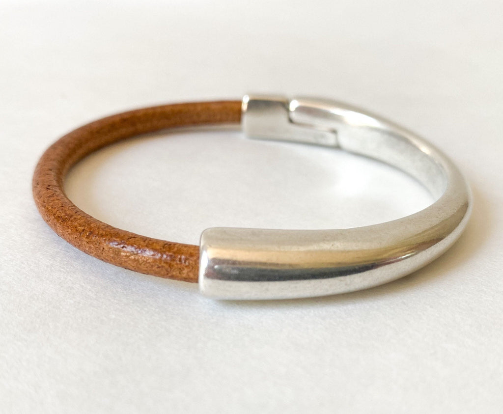 A camel brown leather with silver clasp sits on a white table