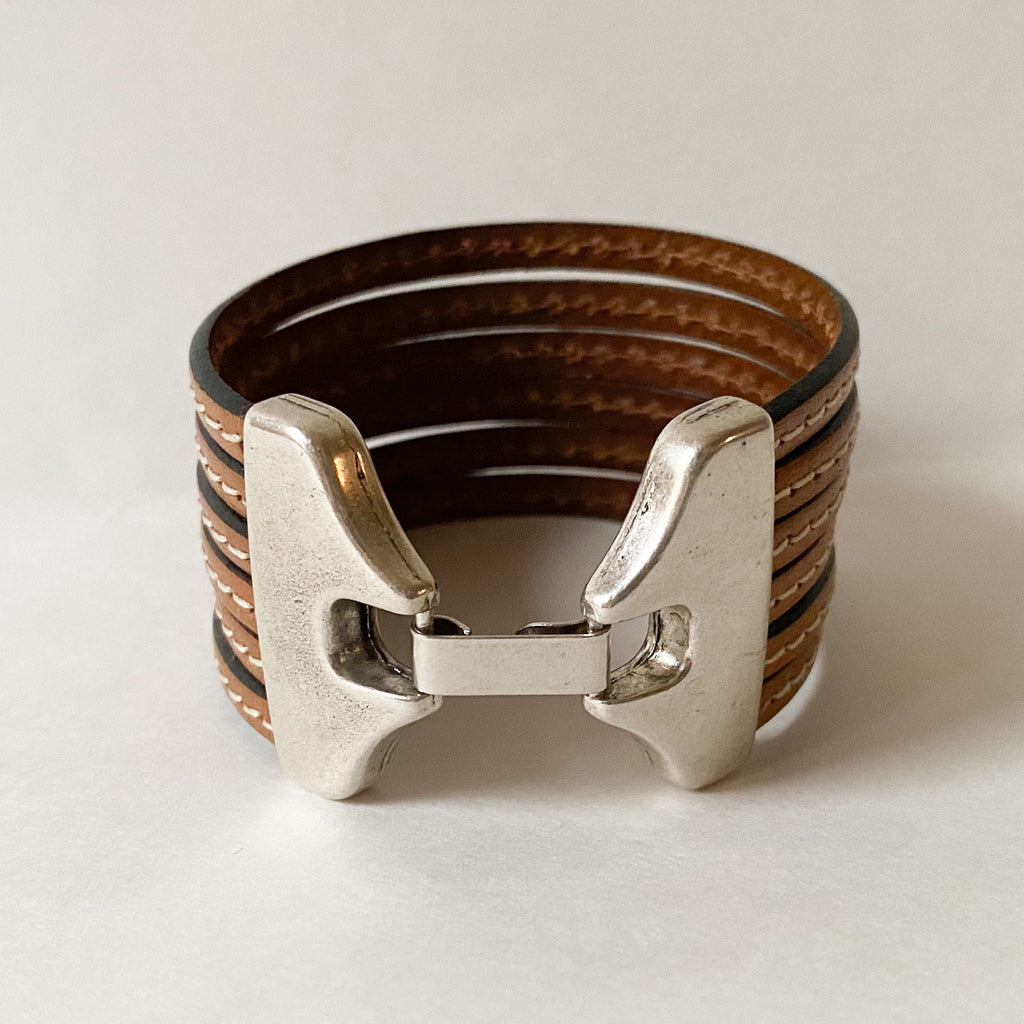 Camel Brown multi strand cuff bracelet with silver clasp sits on a white table