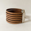 The side of a camel leather multi strand cuff bracelet shows while sitting on a table