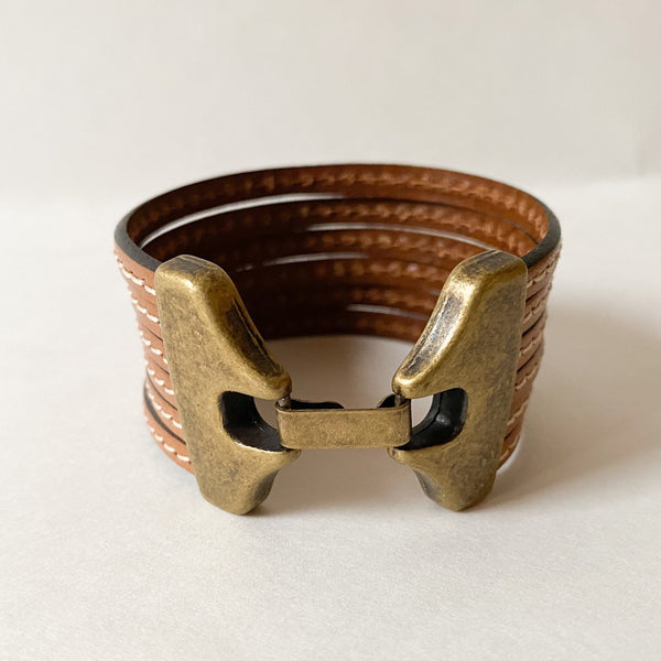 Camel Brown multi strand cuff with antique brass clasp on a white table