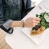 Camel/Cognac Brown Leather Bracelet for Women is worn on a woman's wrist while she eats quiche and salad