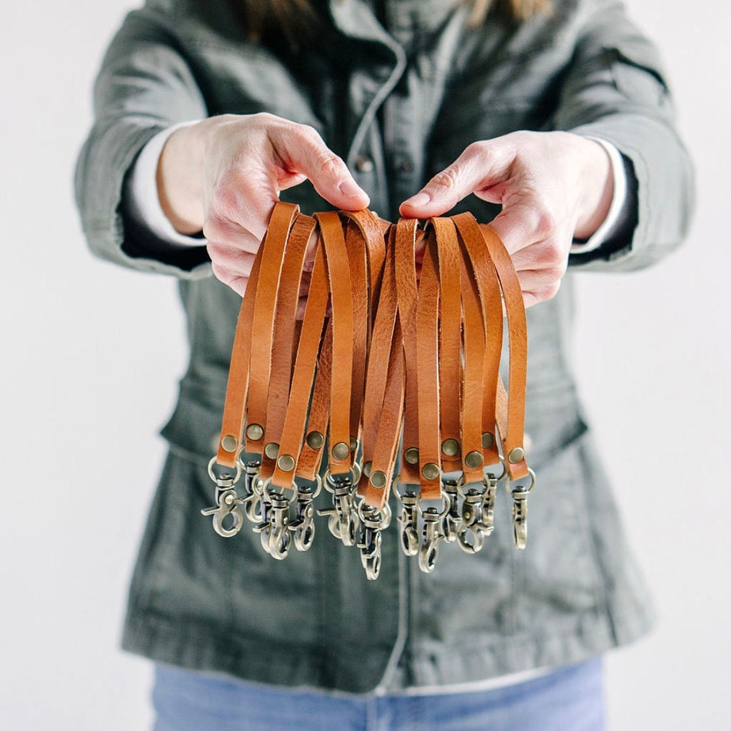 A woman holds a handful of leather wristlet straps with clip attachment