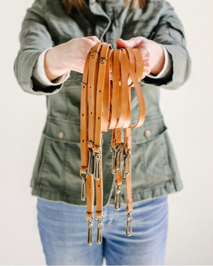 a woman holds a handful of leather crossbody straps